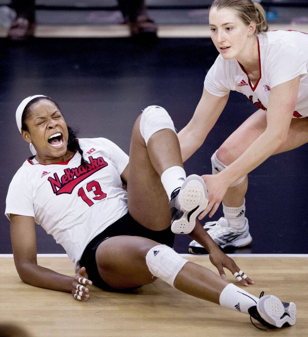 Two women are playing volleyball on the court.
