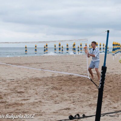 A man is playing tennis on the beach