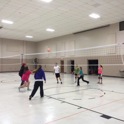 A group of people playing volleyball in an indoor gym.