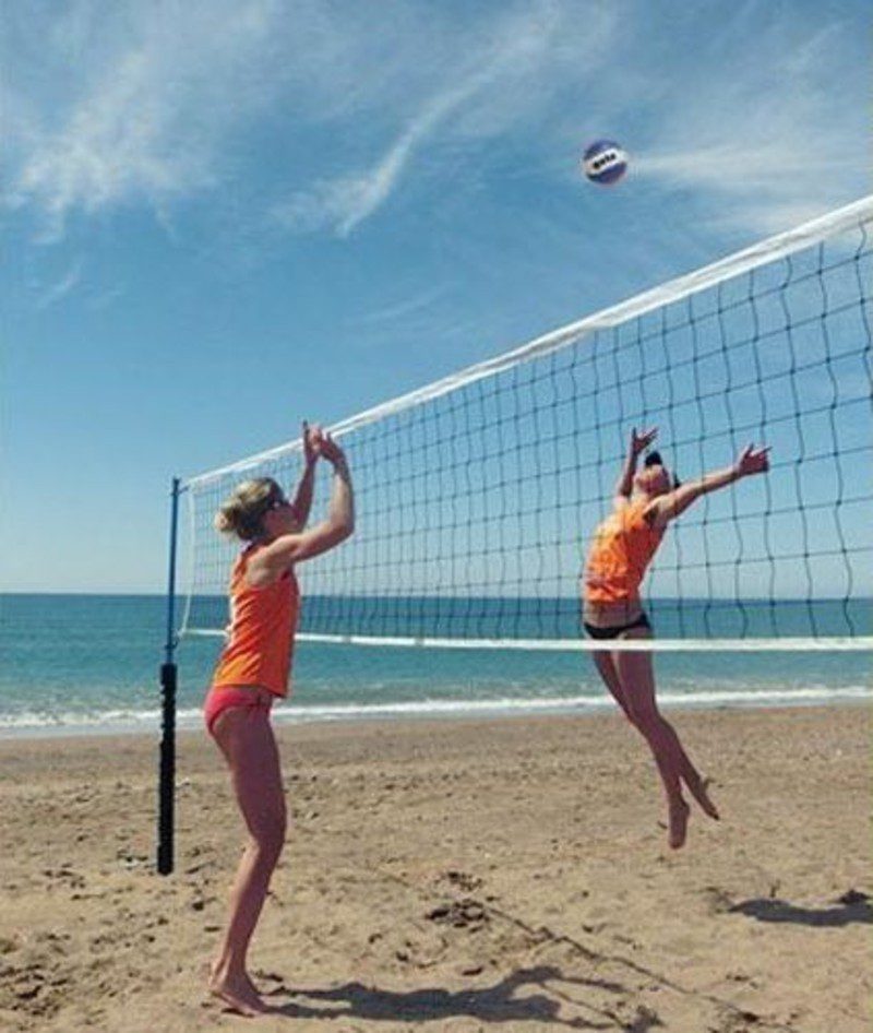 Two women playing volleyball on the beach.