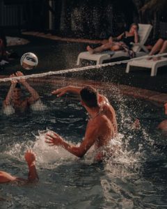 A group of people playing volleyball in a swimming pool 