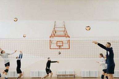 Three people playing volleyball in a gym.