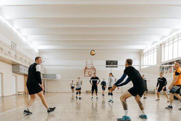 A group of people playing volleyball in an indoor gym.