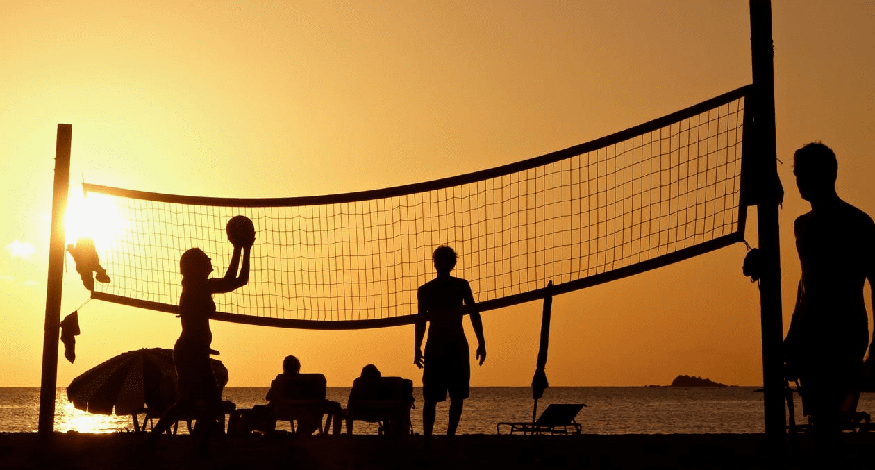 People playing volleyball at the beach.