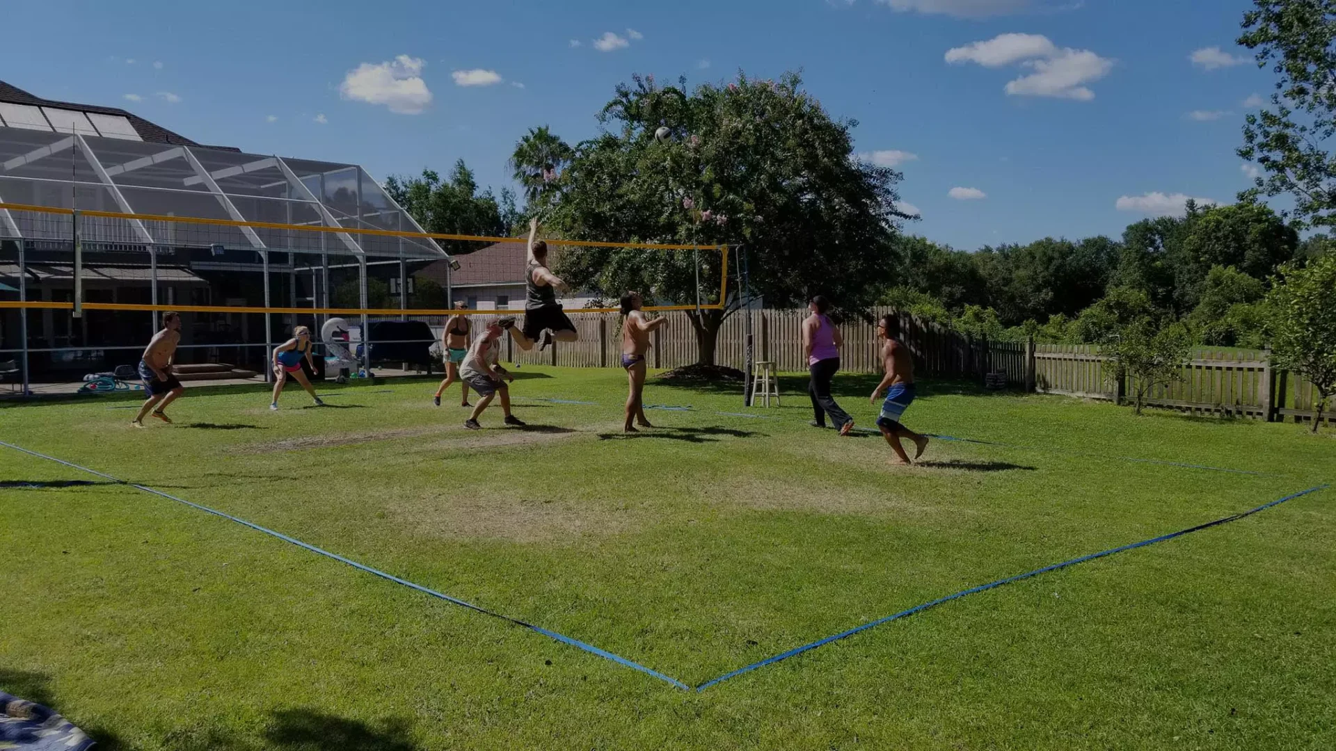 A group of people playing volleyball on the grass.