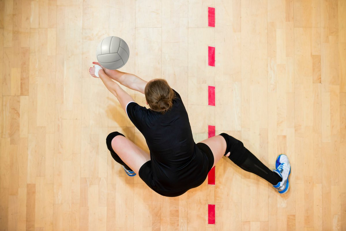 A person on the ground with a volleyball.