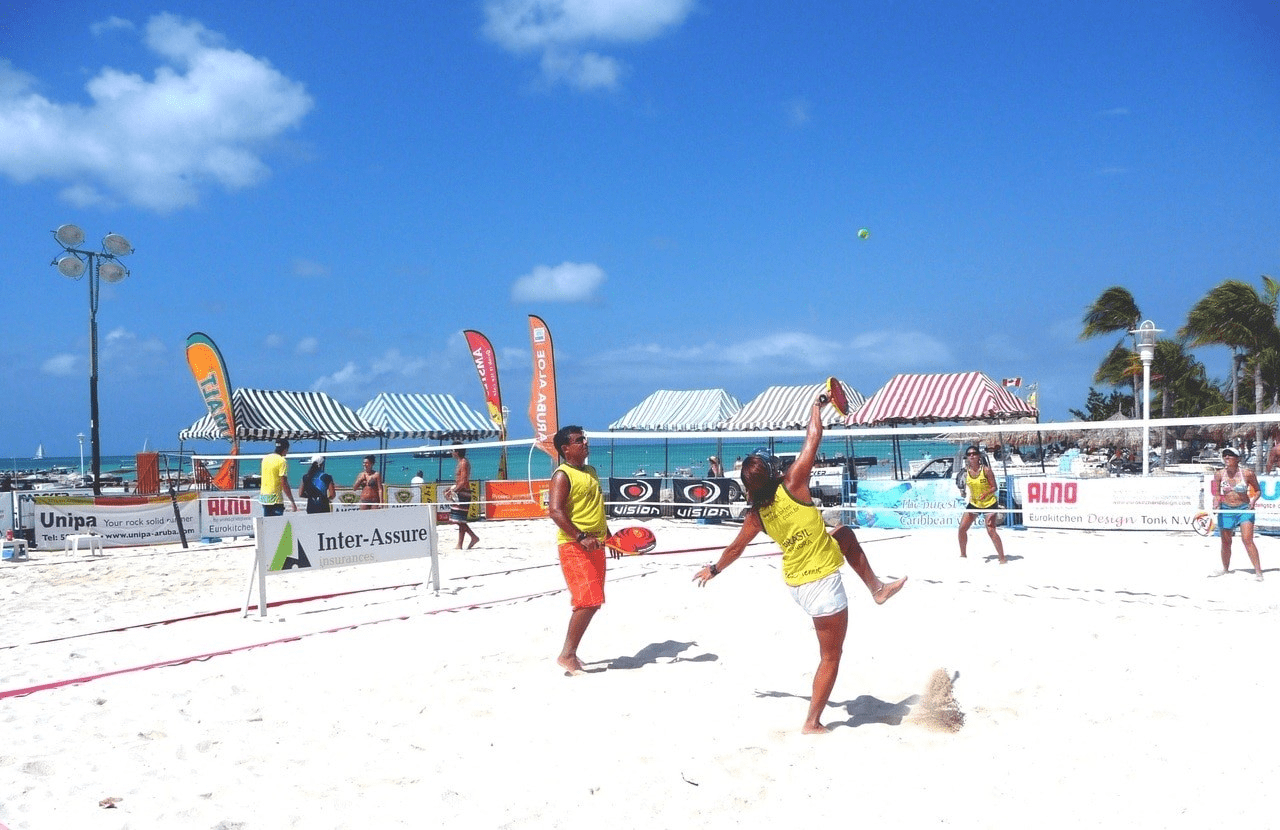 A group of people playing frisbee on the beach.