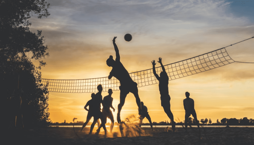 A group of people playing volleyball on the beach.