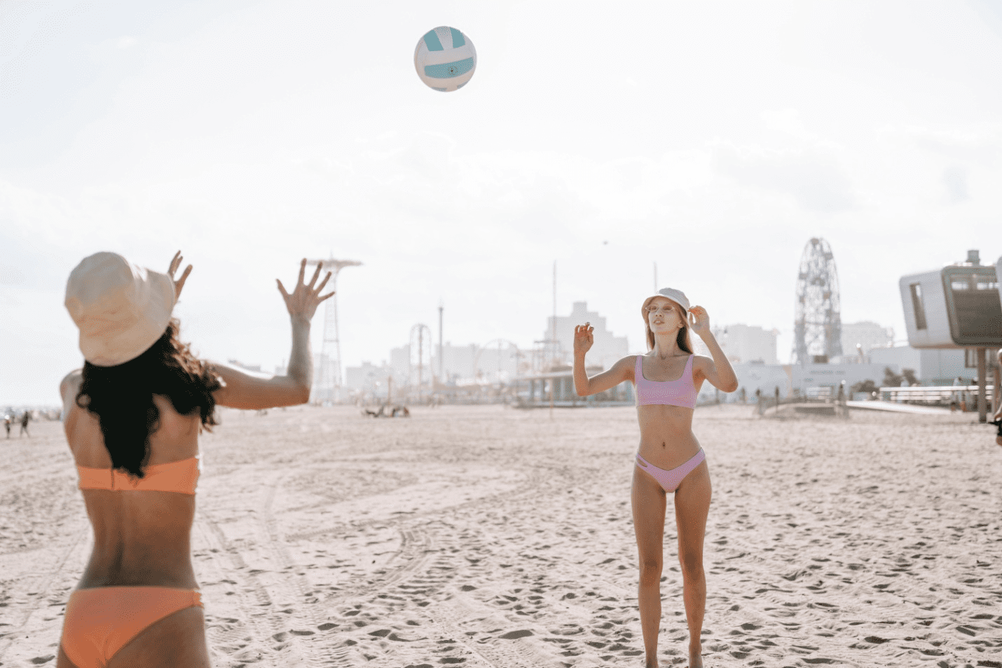 Two women at the beach playing with a volleyball
