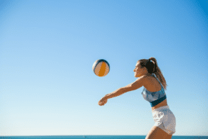 A woman playing with a volleyball at the beach