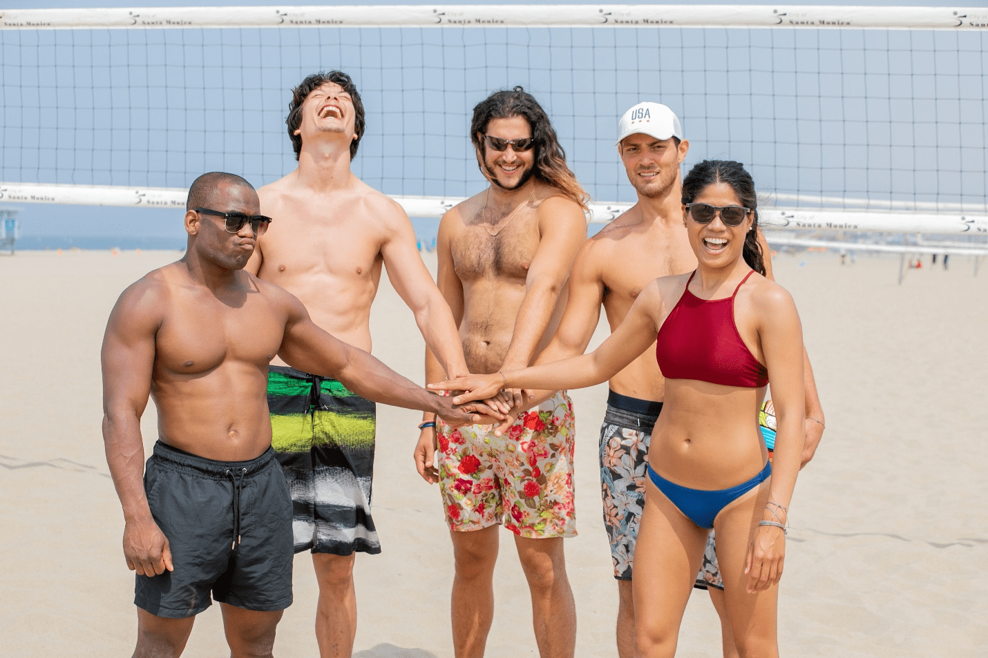A beach volleyball team putting their hands together